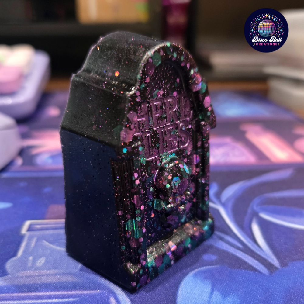 Decorative object with 'Here Lies' text on a colourful background
