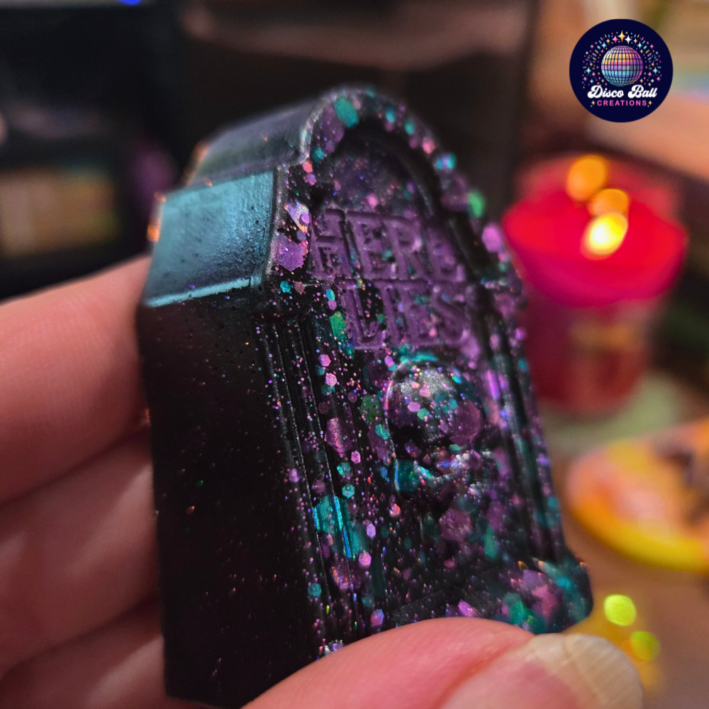 Black glittery grave stone ornament held by a hand with a blurred background
