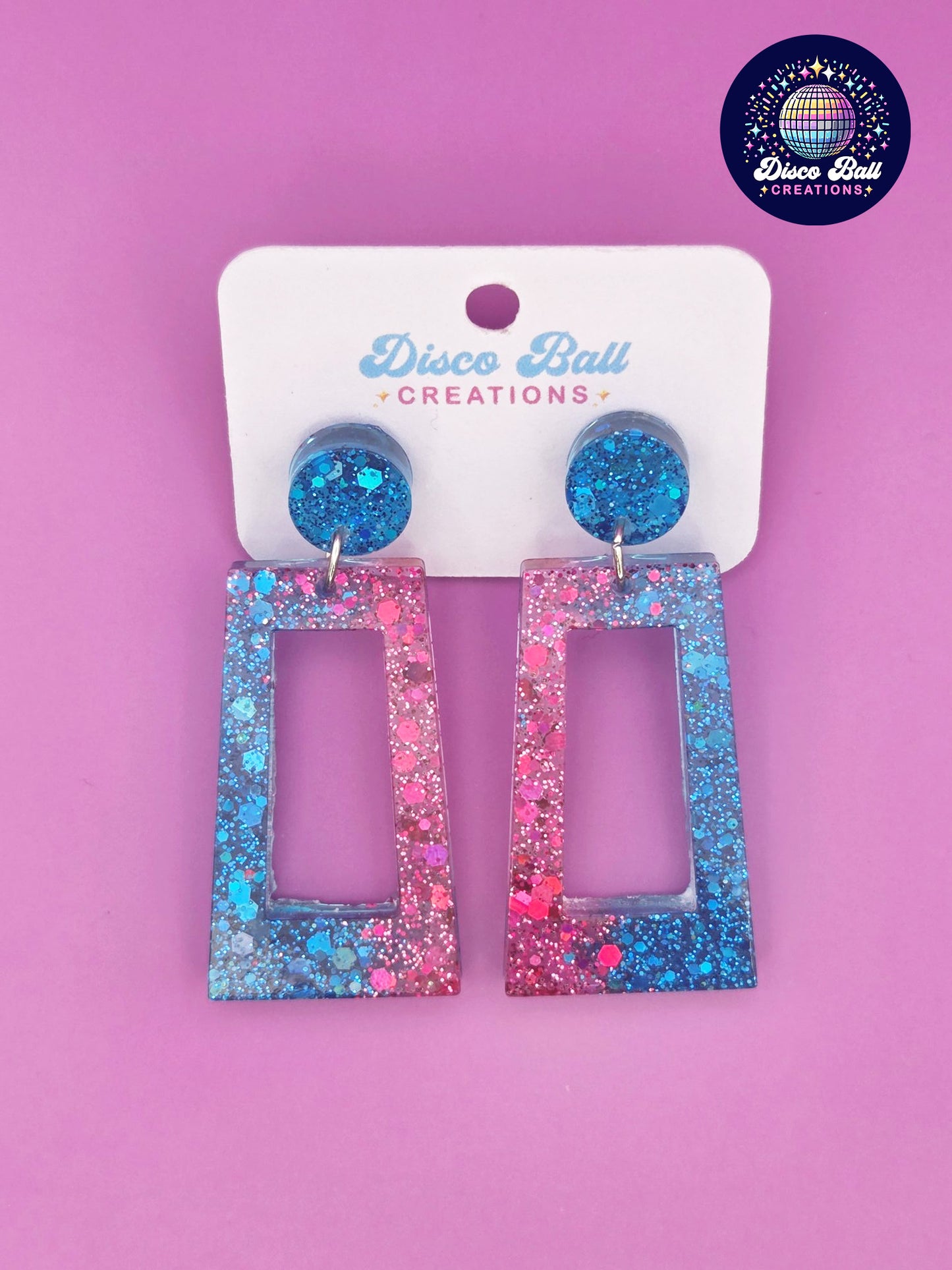 Pink and blue glitter resin rectangle earrings with geometric cut-out design, displayed on a Disco Ball Creations branded card