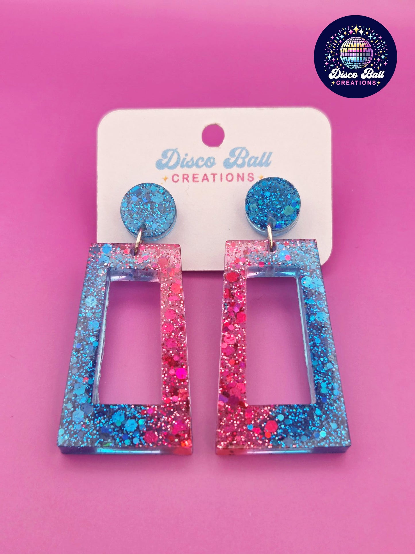 Pink and blue glitter resin rectangle earrings with geometric cut-out design, displayed on a Disco Ball Creations branded card