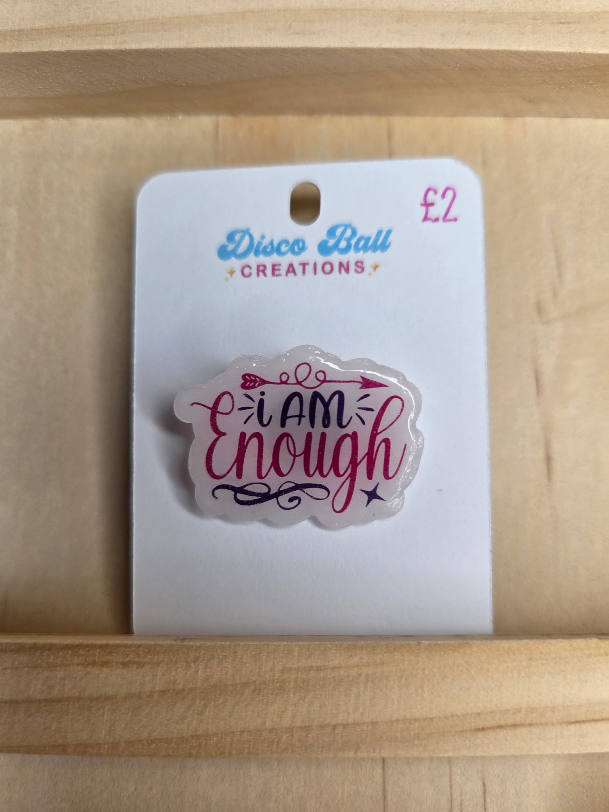 Affirmation pin badge that reads “I am enough” in purple and pink text with stars.