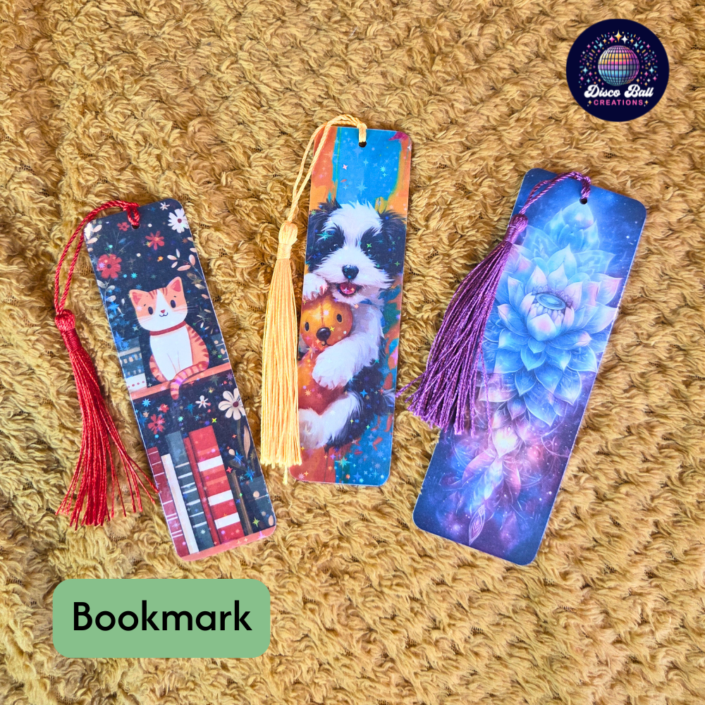 Three colorful bookmarks with tassels on a textured surface, featuring designs of a cat, dog, and abstract pattern.