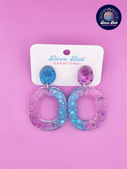 Pink and teal glitter resin oval hoop earrings with chunky sparkle, displayed on a Disco Ball Creations backing card