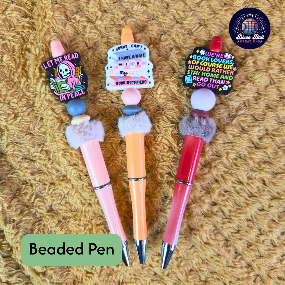 Three beaded pens with colorful accents on a textured surface