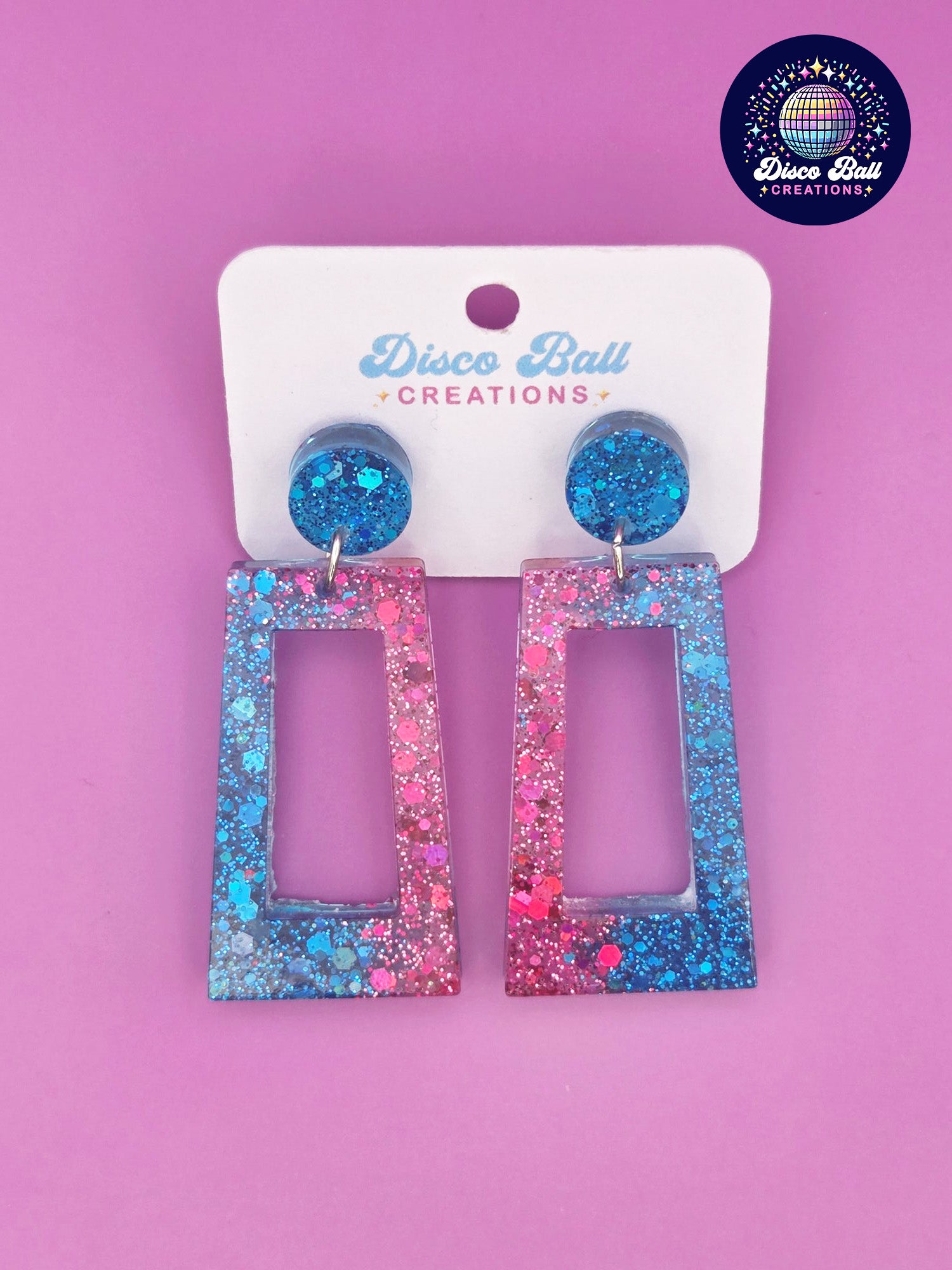 Pink and blue glitter resin rectangle earrings with geometric cut-out design, displayed on a Disco Ball Creations branded card