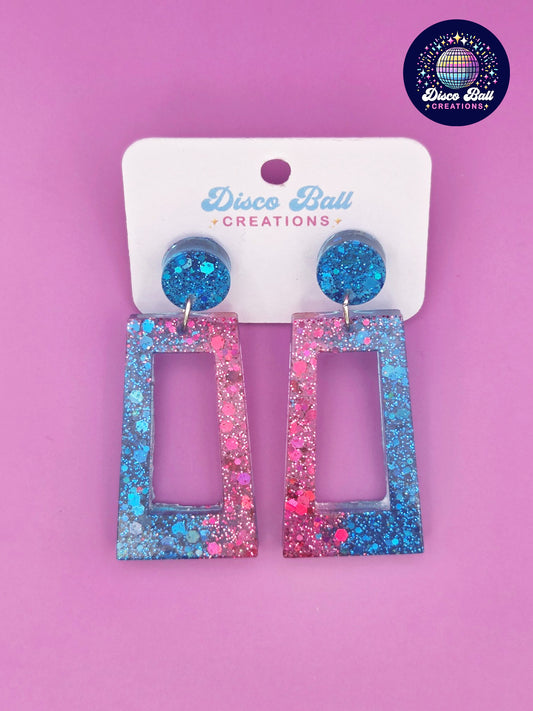 Pink and blue glitter resin rectangle earrings with geometric cut-out design, displayed on a Disco Ball Creations branded card